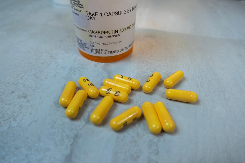 A prescription bottle labeled "Gabapentin 300 mg" is on a countertop with several yellow capsules spilled, to show example of Neuropathic Medications from pain doctors in Schererville.